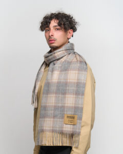 A folded black and grey cashmere scarf with a gift tag.